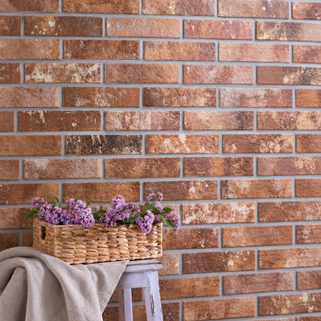 AI-styled interior detail with London Brick Sunset 60x250mm brick-look porcelain wall tiles, a flower basket and linen-covered stool